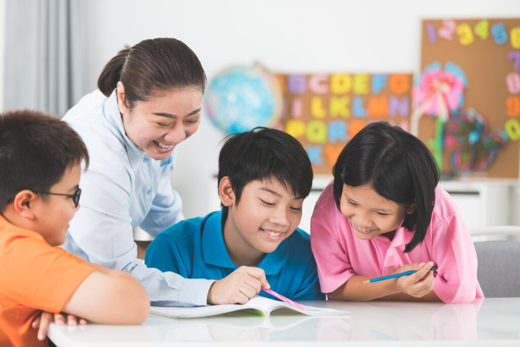 young-asian-teacher-helps-young-school-kids-class